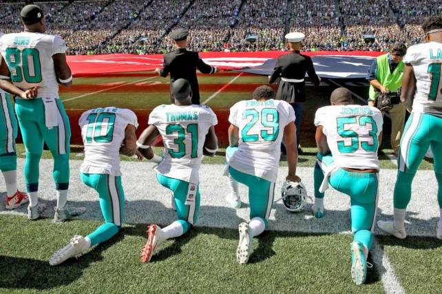 Los jugadores de los Dolphins, Kenny Stills, Michael Thomas, Arian Foster y Jelani Jenkins se arrollidan a modo de protesta.